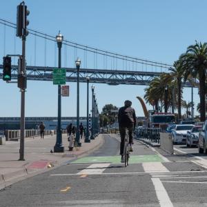 Biking along the Embarcadero in the designated bike lanes overlooking the Bay Bridge and waterfront view 