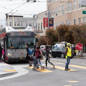 Students boarding the 30 Stockton bus, as well as crossing the street to catch the bus. 