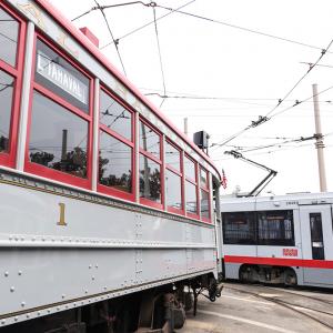 Muni streetcar 1 and new light rail vehicle in yard, both painted grey and red.