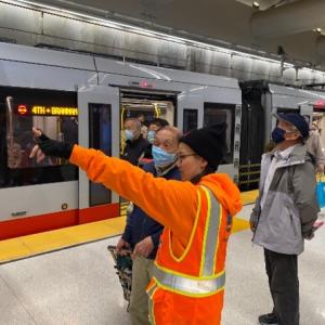 SFMTA Ambassador talking to customers on Metro station platform.
