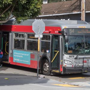 Coach approaching a bus stop along the curb with their door open. 