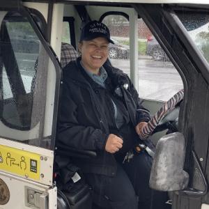Parking Control Officer in uniform smiling while sitting inside a parking enforcement vehicle.