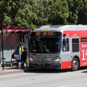 People at a bus stop boarding the 28R bus on 19th Avenue.