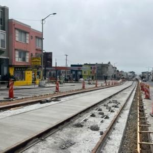A track under construction on a city street with orange bollards on each side.