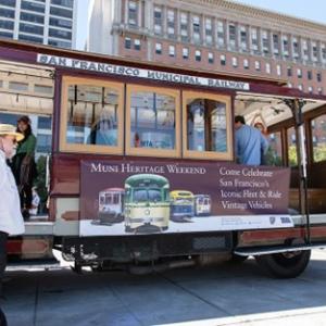 A San Francisco Cable Car with a banner that says Muni Heritage Weekend on the side.