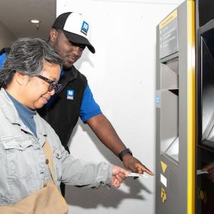 Ambassador helping a customer at a parking payment machine at an SFMTA lot