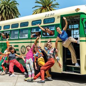 A group of people pose around a vintage bus.