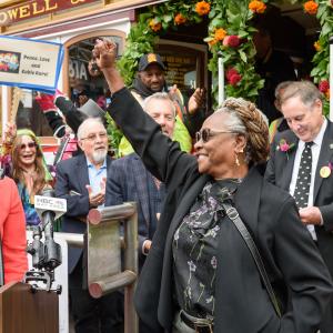 People celebrating in front of a decorated San Francisco cable car and a woman standing in front holding her fist in the air.