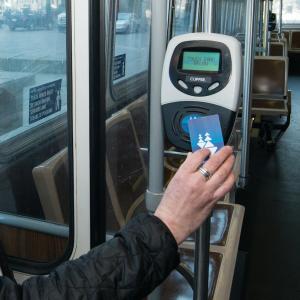 Person sitting on a bus taps their clipper card.