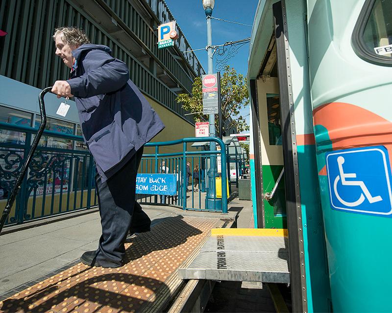 older man with cane exiting historic streetcar at high level boarding platform