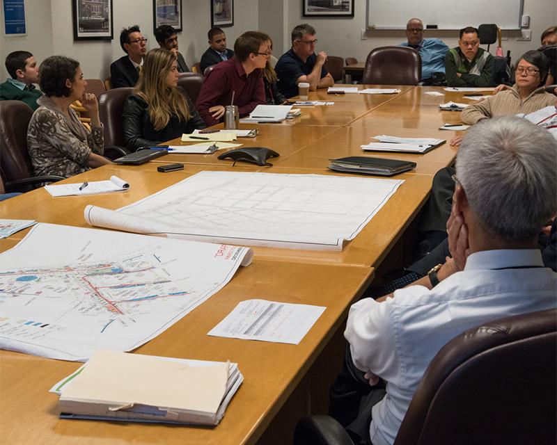 group of people around a large meeting table with papers on table