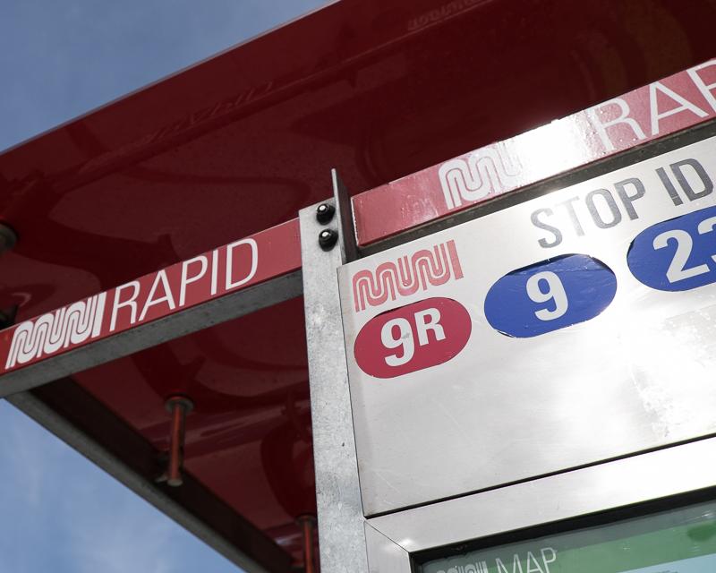 closeup of muni bus shelter with route designation stickers and signage