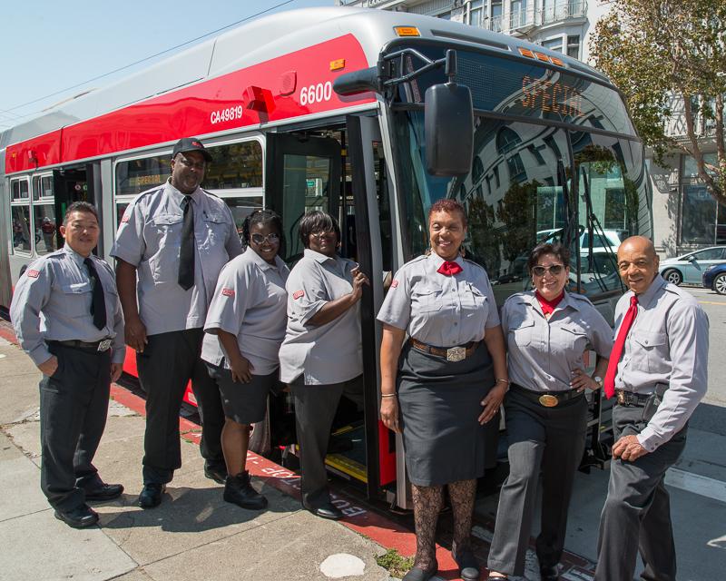 group of transit operators standing with new articulated coach