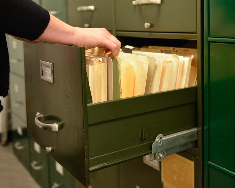 person flipping through files in a filing cabinet drawer