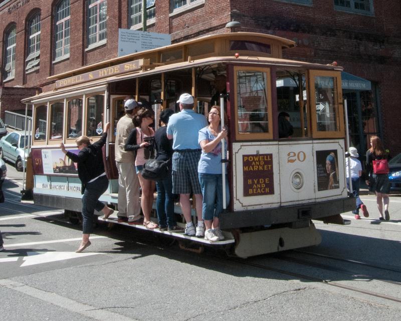 cable car with people on board stopped in intersection to unload