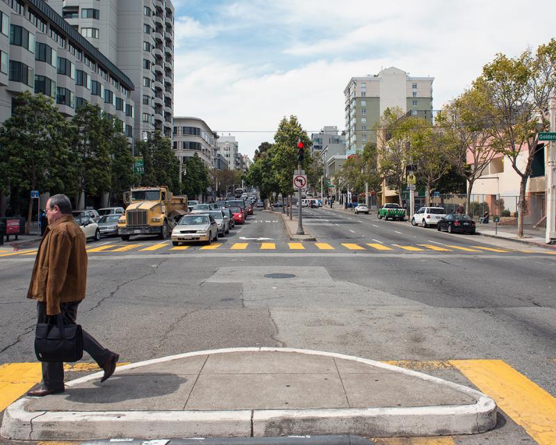 A pedestrian crosses the street at Golden Gate Avenue and Van Ness Avenue